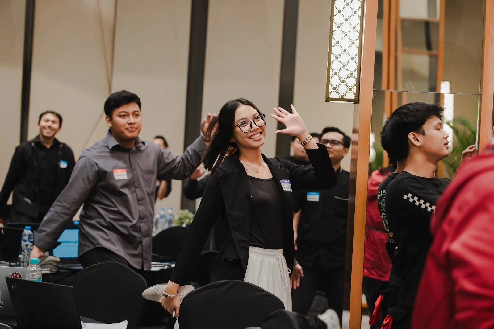 Attendees raising their hands and smiling during a session